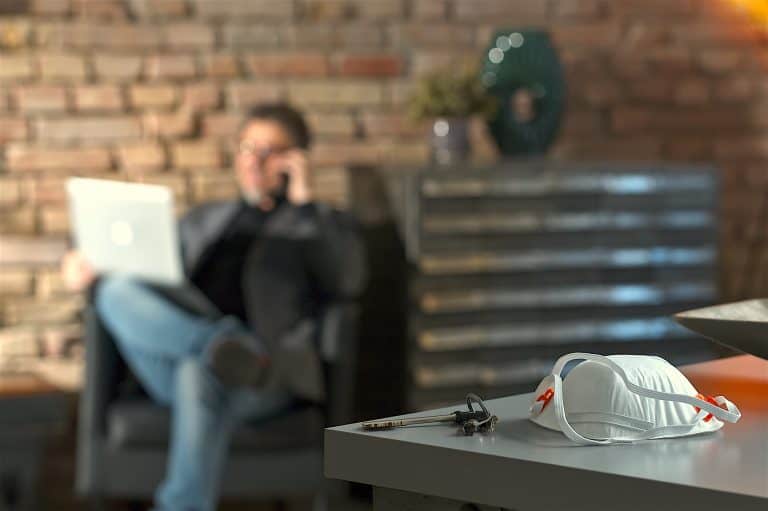 Covid-19 virus danger - Businessman working at safety of home office leaving virus protective mask o