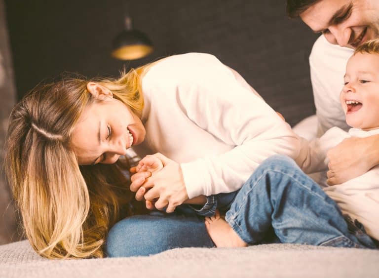 Parents With Their Baby Boy On Bed At Home. Families With Child In Bed At Night At Home. Happy Famil